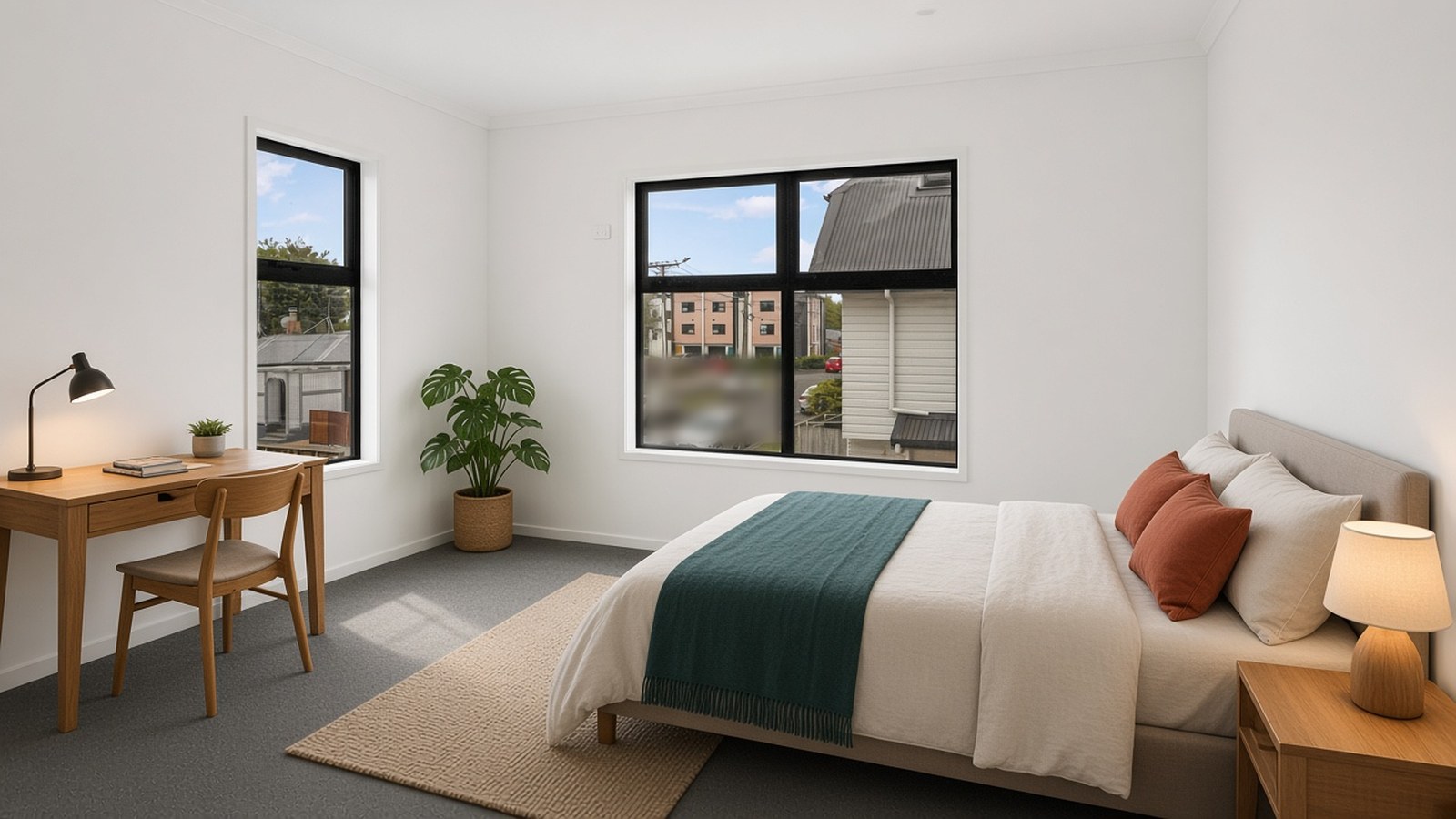 Calm bedroom with a made double bed, teal throw and terracotta cushions, plus a wooden study desk and lamp by the window.